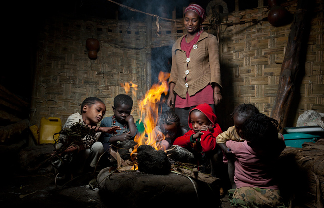 A Dorze woman looking with care at the children seated around the fire (Ethiopia - 2013)