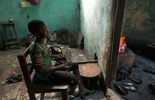 A young boy permanently ventilates the fire to keep it constantly at the same temperature.