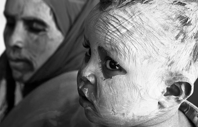 Pilgrims cover themselves with a coating of white pigment from the white wall of the mausoleum.