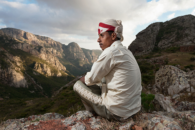 Ahmed, a camel man, standing at the Daadha pass in front of the granite Haggier mountains. Socotra - Yemen - 2020
