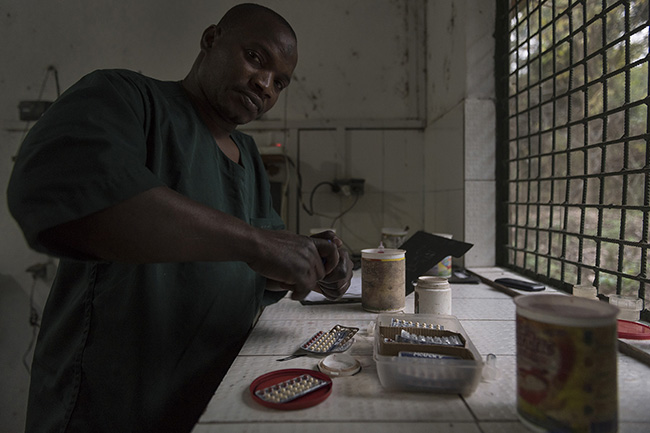 Sadou, a caregiver at the Chimpanzee Conservation Center in Guinea, prepares and grinds contraceptives for the pubescent females. All pubescent females at the sanctuary are placed on contraceptives to prevent captive births.